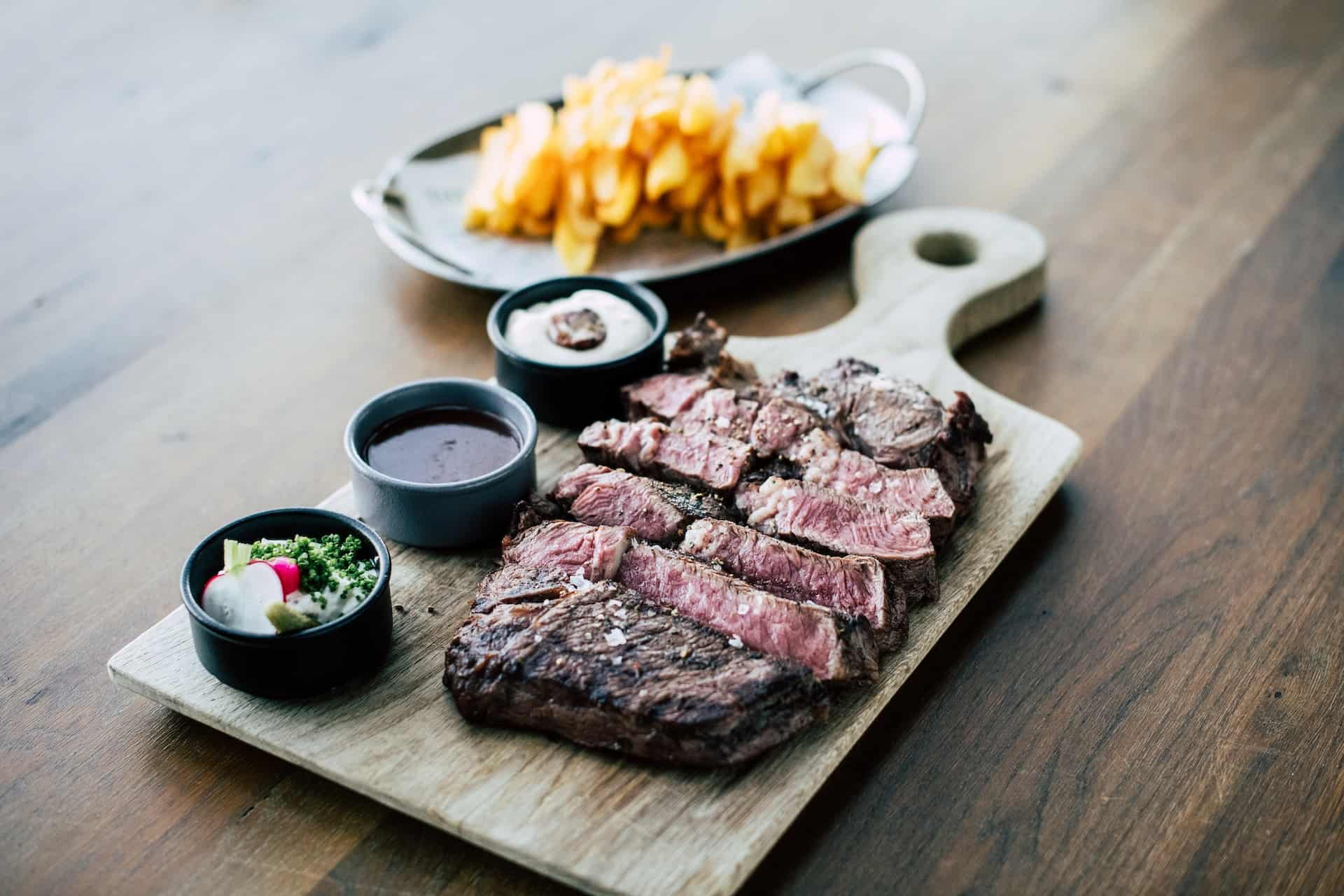 Steak on a cutting board with fries.